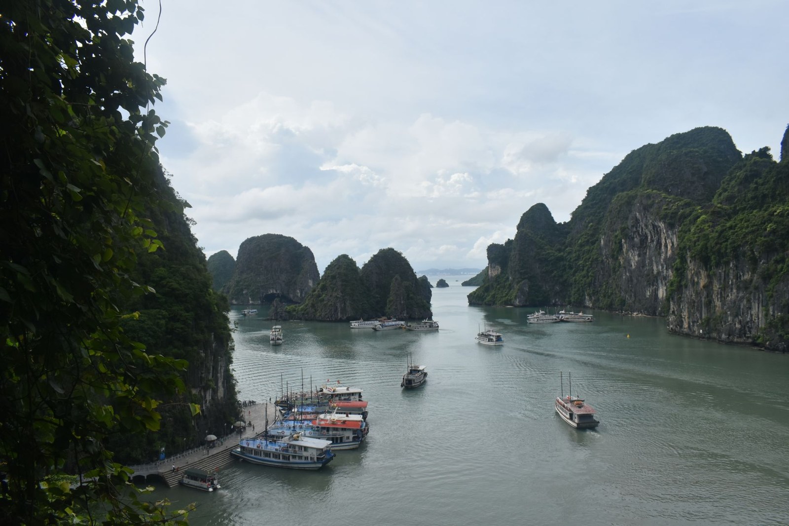 Limestone islands rising from the water of Ha Long Bay with boats moored below
