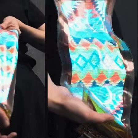 LG Display’s illuminated stretchable display being flexed by hand.