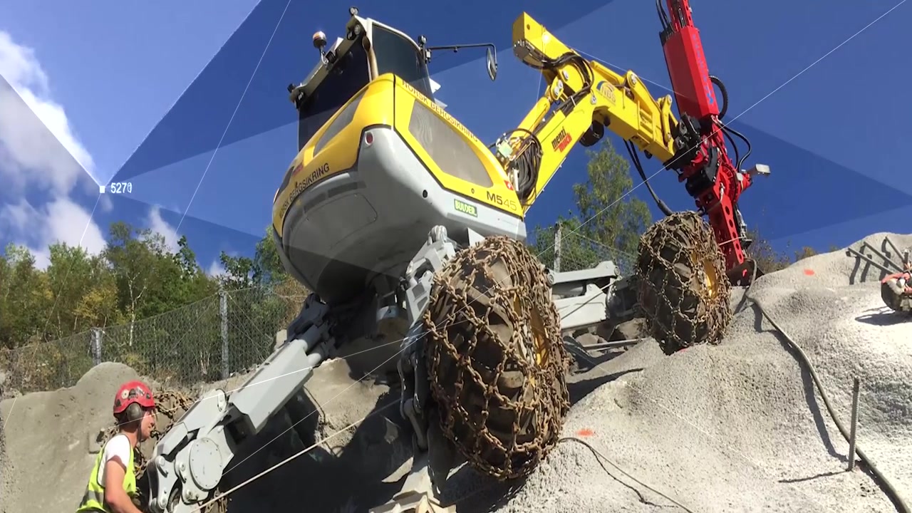 A yellow Menzi Muck walking excavator working on a steep rocky site